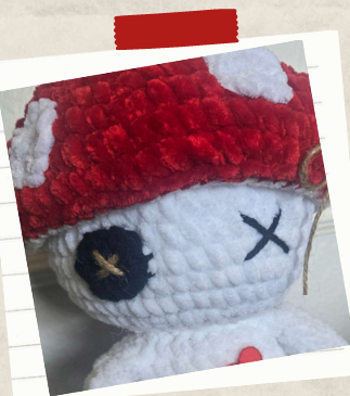 Embroidered facial details on a plushy crochet mushroom doll