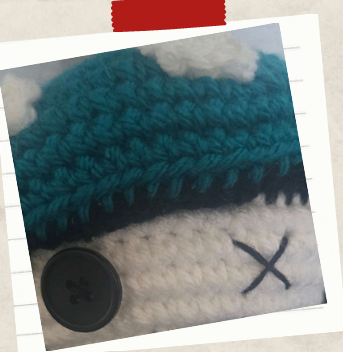 embroidered X eye and button eye on a toadstool crochet doll