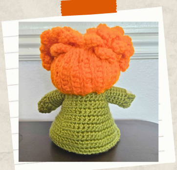 Free witch crochet pattern with curly orange hair and green coat.