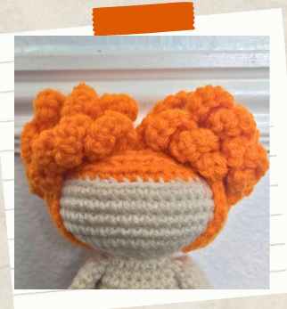 Free witch crochet pattern with curly orange hair styled into poufs.