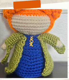 Free witch crochet pattern with curly orange hair and green coat.
