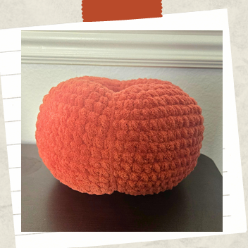 Cute Halloween crochet pumpkin decoration displayed on a rustic wooden surface