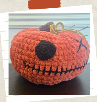 Spooky crochet pumpkin poppet with embroidered details and plush chenille yarn