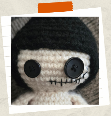 Crocheted witch head with button eyes and stitched smile detail.