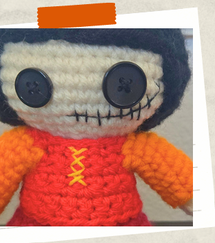 Amigurumi witch head showing embroidered mouth and button eyes.