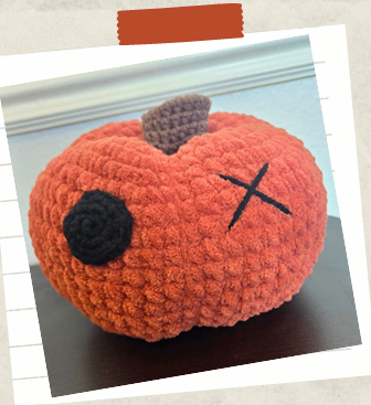 Close-up of stitched smile and button eye on crochet pumpkin plush