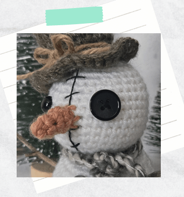 A tutorial photo showing a crochet snowman's nose placement