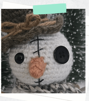 A close up of a crochet snowman pattern showing face details