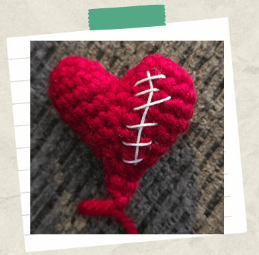 A tutorial picture showing a completed crochet heart with decorative embroidered stitches.