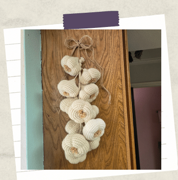 a tutorial photo showing a crochet garlic braid hanging on a cabinet