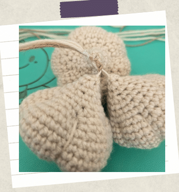 A tutorial picture showing the fastening of three crochet garlic bulbs